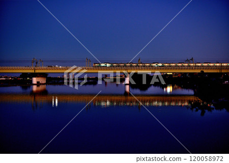 Noborito: Odakyu Line trains shining in the setting sun as seen from upstream the Tama River bank 120058972