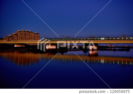 Noborito: Odakyu Line trains shining in the setting sun as seen from upstream the Tama River bank 120058975