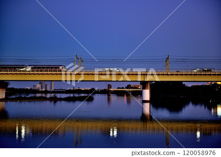 Noborito: Odakyu Line trains shining in the setting sun as seen from upstream the Tama River bank 120058976