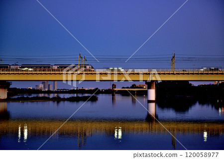 Noborito: Odakyu Line trains shining in the setting sun as seen from upstream the Tama River bank 120058977