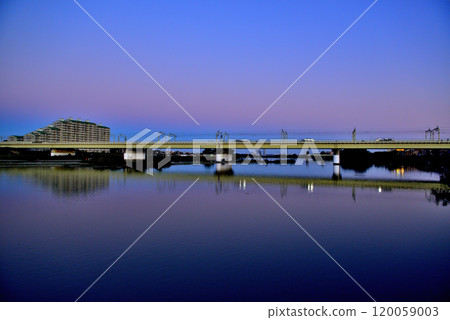 Noborito: Odakyu Line trains shining in the setting sun as seen from upstream the Tama River bank 120059003