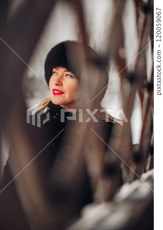 A beautiful woman in a black fur coat and a black A beautiful woman in a black fur coat and a black 120059067