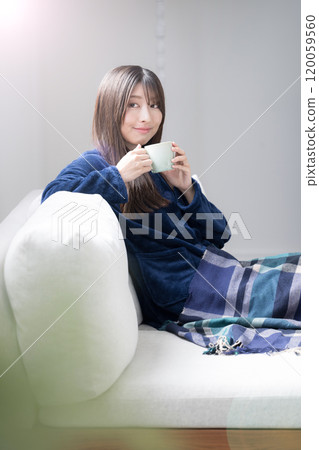 Woman in cute winter pajamas relaxing in the living room, vertical 120059560