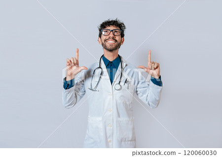 Handsome doctor pointing up. Smiling doctor pointing a promo up. Male doctor looking and pointing up isolated Handsome doctor pointing up. Smiling doctor pointing a promo up. Male doctor looking and pointing up isolated 120060030