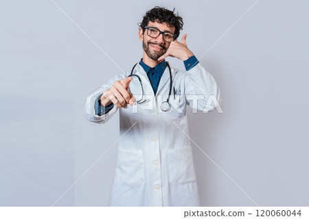 Smiling doctor making call gesture and pointing at the camera. Young doctor making call gesture isolated Smiling doctor making call gesture and pointing at the camera. Young doctor making call gesture isolated 120060044