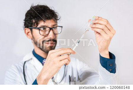 Handsome Doctor drawing medicine from a vial isolated. Young doctor drawing medicine from a vial isolated. Concept of doctor with disease antidote Handsome Doctor drawing medicine from a vial isolated. Young doctor drawing medicine from a vial isolated. Concept of doctor with disease antidote 120060148