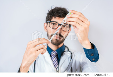 Doctor drawing medicine from a vial isolated. Young doctor drawing medicine from a vial with copy space. Concept of doctor with disease antidote 120060149
