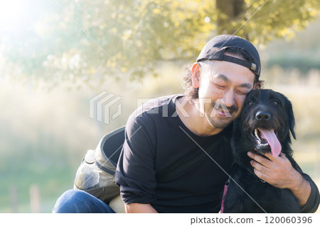 The upper body of a large pet dog and its male owner in a place with beautiful autumn leaves 120060396
