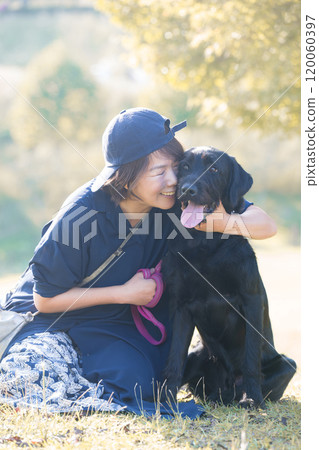 A large pet dog and its owner, a woman, in a place with beautiful autumn leaves, full body A large pet dog and its owner, a woman, in a place with beautiful autumn leaves, full body 120060397