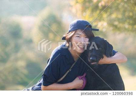 A large pet dog and its female owner in a place with beautiful autumn leaves, upper body looking at camera A large pet dog and its female owner in a place with beautiful autumn leaves, upper body looking at camera 120060398