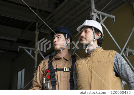 兩名高空作業人員和繫著安全帶的戶外工作人員抬頭仰望，表情嚴肅嚴肅。 120060483