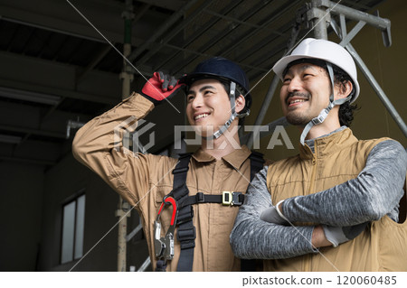 兩名高空作業人員和戴著安全帶的戶外工作人員的笑臉向上看，旁邊有影印空間 120060485
