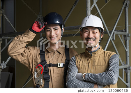 兩名戴著安全帶在戶外工作的高空作業工人和其他體力勞動者的笑臉。 兩名戴著安全帶在戶外工作的高空作業工人和其他體力勞動者的笑臉。 120060486