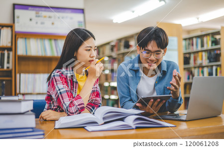 Students are consulting each other working on laptops and searching for books to study, make reports, find useful information in university room. Concept of reading, learning and intelligence. 120061208