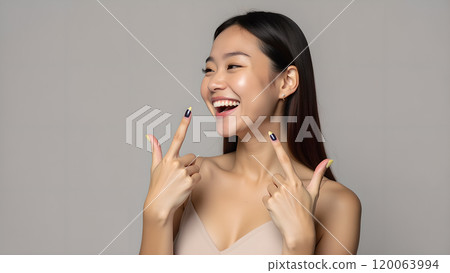 Asian Woman Happily Pointing to Upper Side with Both Fingers in Studio 120063994
