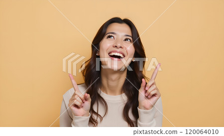Asian Woman Happily Pointing to Upper Side with Both Fingers in Studio 120064010