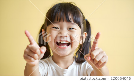 Asian Woman Happily Pointing to Upper Side with Both Fingers in Studio Asian Woman Happily Pointing to Upper Side with Both Fingers in Studio 120064046
