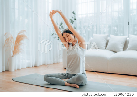 Happy young Asian woman practicing yoga and shoulder stretching at home Happy young Asian woman practicing yoga and shoulder stretching at home 120064230