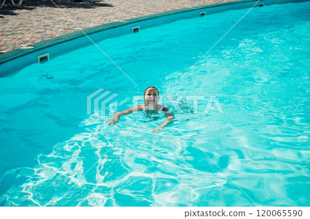 A woman is swimming in a pool. The pool is surrounded by a fence and has a playground in the background. A woman is swimming in a pool. The pool is surrounded by a fence and has a playground in the background. 120065590