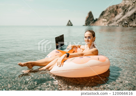 Woman laptop sea. Freelancer woman in sunglases floating on an inflatable big pink donut with a laptop in the sea. People summer vacation rest lifestyle concept 120066616