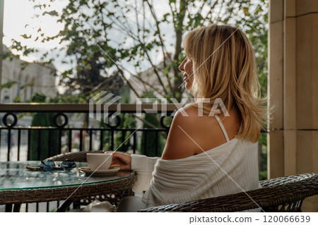Woman Balcony Coffee Relaxation - Woman enjoys her morning coffee on a balcony overlooking a city. 120066639