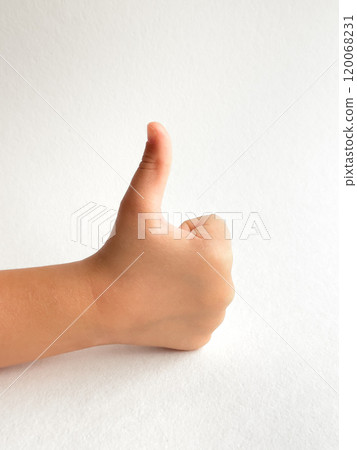 Childs hand giving a thumbs up with neutral background for positivity concept 120068231