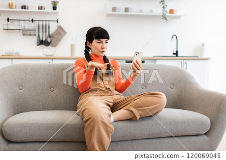 Young woman having video call on smartphone at home Young woman having video call on smartphone at home 120069045