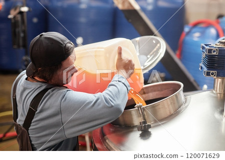 High angle shot of male production worker pouring apple juice from plastic container into stainless steel tank making craft cider in workshop of factory, copy space High angle shot of male production worker pouring apple juice from plastic container into stainless steel tank making craft cider in workshop of factory, copy space 120071629