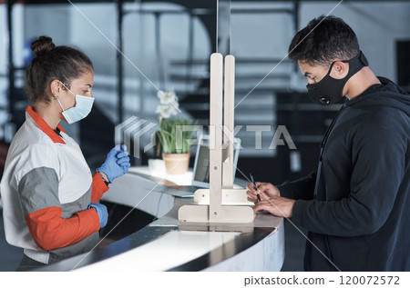 Please fill in this short questionnaire before entering. Shot of a young man filling in paperwork at the reception desk of a gym. 120072572