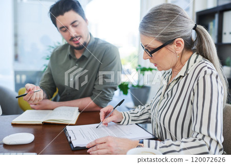 Ensuring their paperwork is up to date. Shot of two businesspeople going through paperwork together in an office. 120072626
