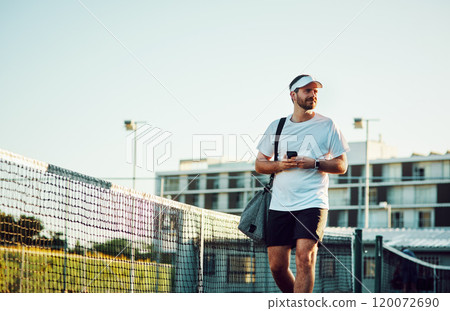 My partner should be here any minute now. Shot of a sporty young man using a cellphone while walking on a tennis court. My partner should be here any minute now. Shot of a sporty young man using a cellphone while walking on a tennis court. 120072690