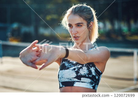 Prepping with some stretches. Shot of a sporty young woman stretching her arms while exercising on a tennis court. Prepping with some stretches. Shot of a sporty young woman stretching her arms while exercising on a tennis court. 120072699