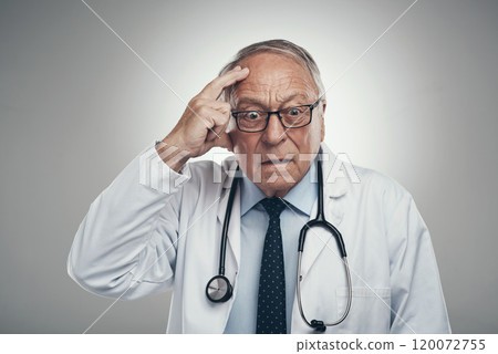 Hmm Ill need to think on this. Shot of an elderly male doctor grasping his head in a studio against a grey background. Hmm Ill need to think on this. Shot of an elderly male doctor grasping his head in a studio against a grey background. 120072755