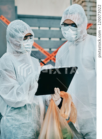 The virus fighting team is on the scene. Shot of two healthcare workers wearing hazmat suits working together to control an outbreak. 120073022