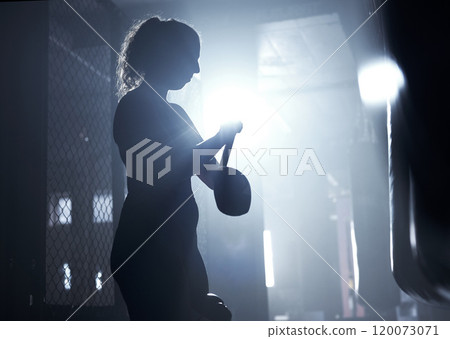 Get ready to prove your worth to the world. Shot of a sporty young woman strapping her gloves while boxing in a gym. Get ready to prove your worth to the world. Shot of a sporty young woman strapping her gloves while boxing in a gym. 120073071