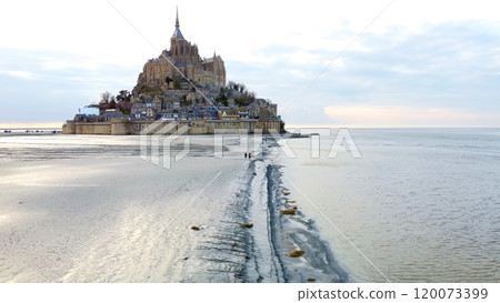 Visitors approaching Mont Saint Michel, Normandy, France across tidal flats Visitors approaching Mont Saint Michel, Normandy, France across tidal flats 120073399