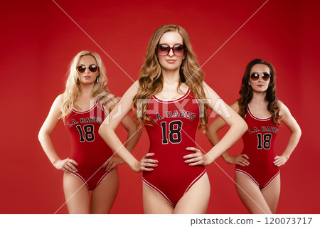 Three women in red swimsuits on a red background 120073717