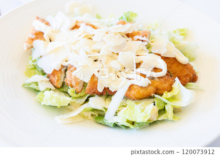 Delicious Caesar salad topped with chicken cutlet and cheese 120073912