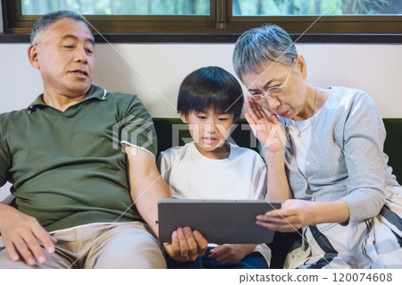 一對老年夫妻與孫子一起看平板電腦，但卻患有老花眼 120074608