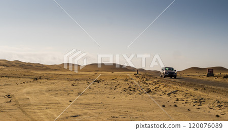Car of tourists crossing the desert in Paracas through a scenic dirt road, Peru 120076089