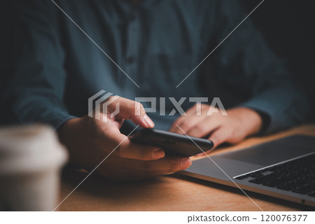 Businessman using smartphone at desk, laptop nearby. Represents digital communication, multitasking. Ideal for tech, corporate themes. Businessman using smartphone at desk, laptop nearby. Represents digital communication, multitasking. Ideal for tech, corporate themes. 120076377