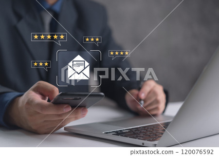 Hand holding a smartphone with email icon and star ratings indicating customer feedback. 120076592