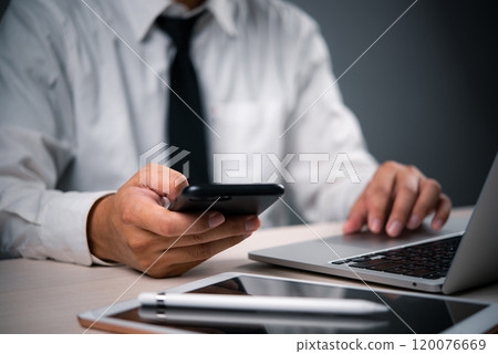 business professional multitasking using a smartphone and laptop, modern digital technology communication and multitasking in corporate environments. 120076669