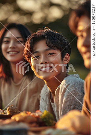 Smiling young asian man enjoying an outdoor gathering with friends 120078237