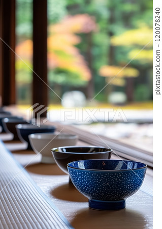 ow of traditional Japanese tea bowls in varied colors, arranged by window 120078240