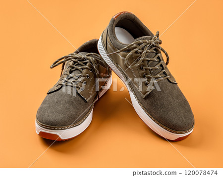 Laced up khaki canvas shoes over orange background. Laced up khaki canvas shoes over orange background. 120078474