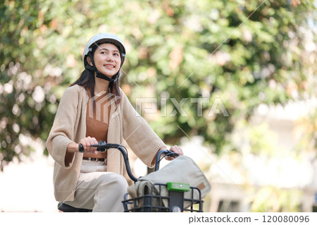 A woman is riding a bicycle with a basket on the front A woman is riding a bicycle with a basket on the front 120080096