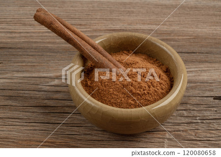 cinnamon powder and stick in a bowl on wooden table cinnamon powder and stick in a bowl on wooden table 120080658