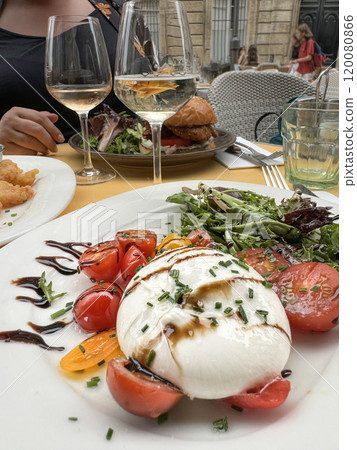 burrata cheese salad and wine glasses on table burrata cheese salad and wine glasses on table 120080866