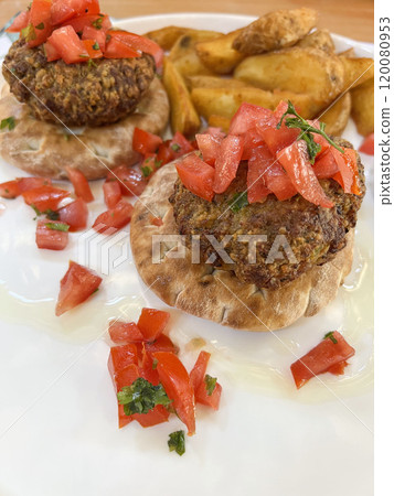 grilled meatballs on bread buns with tomato salad 120080953